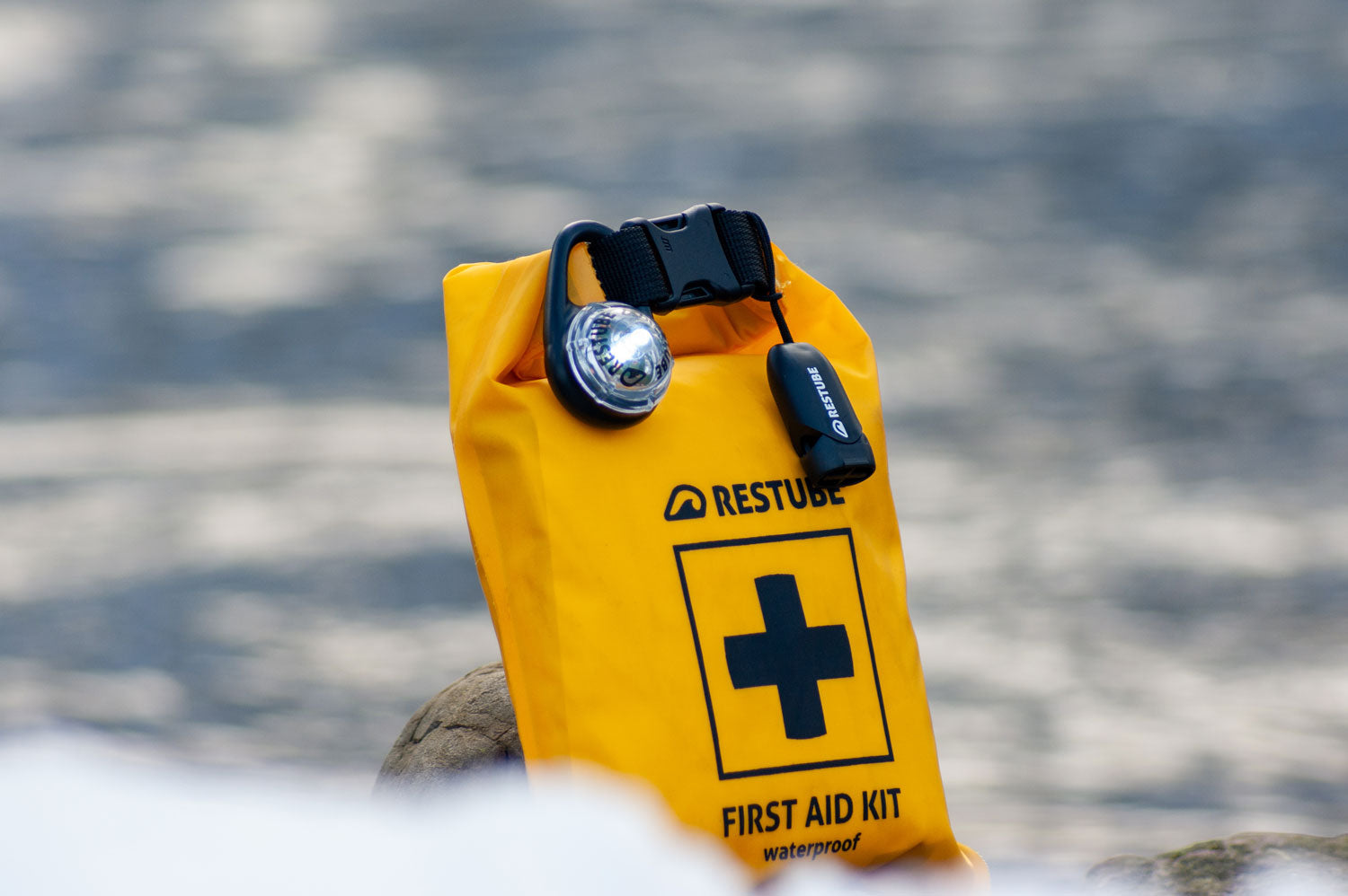 Waterproof first aid kit in front of a river with an LED attached
