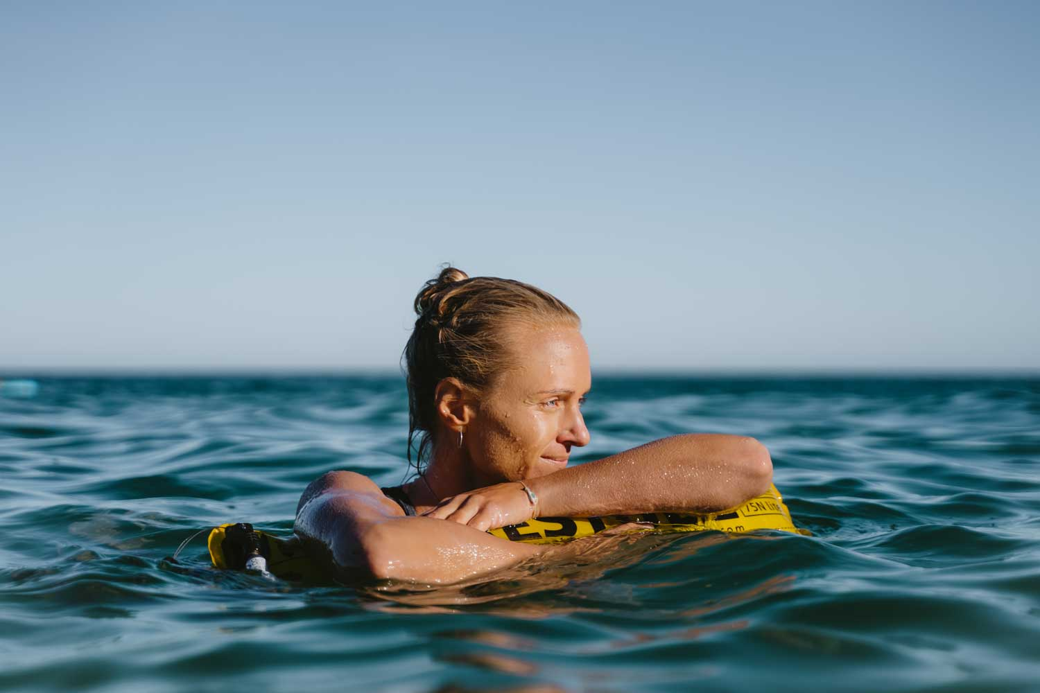 Frau leht sich auf die Restube active und schwimmt im Meer
