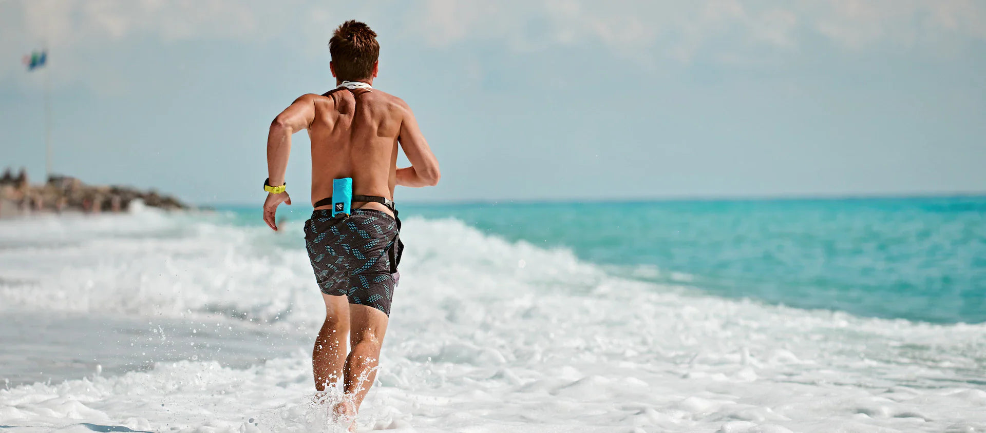 Schwimmer rennt mit verpackter Restube Boje am Rücken durchs Wasser.