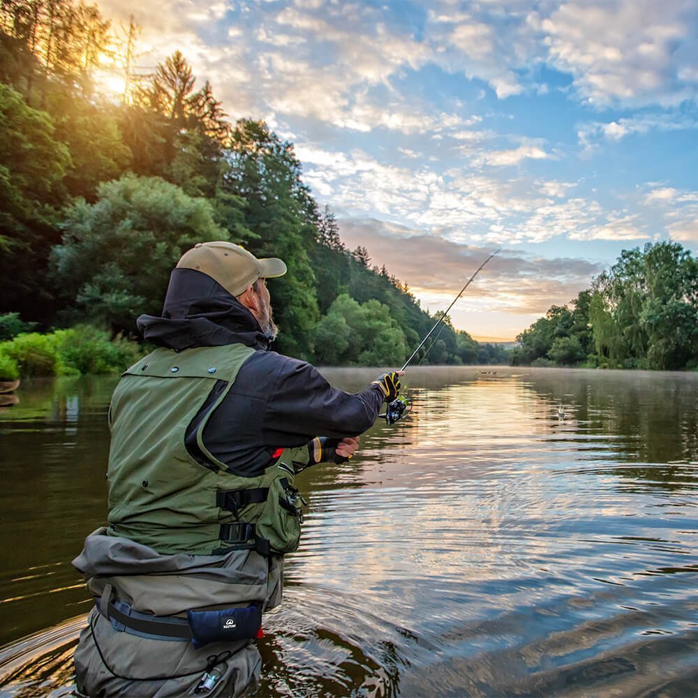 Angler in Wathose mit Restube steht im Fluss und wirft die Angel aus.